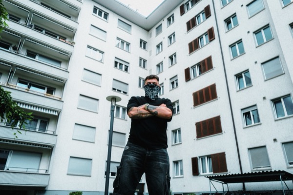 GABU mit Bandana vor einem Wohnblock