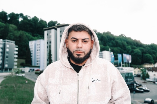 GABU im weissen Kapuzenpullover vor Hochhäusern