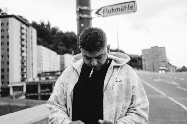 GABU mit Kapuze und Zigarette vor einem Hochhaus, Schwarzweiss