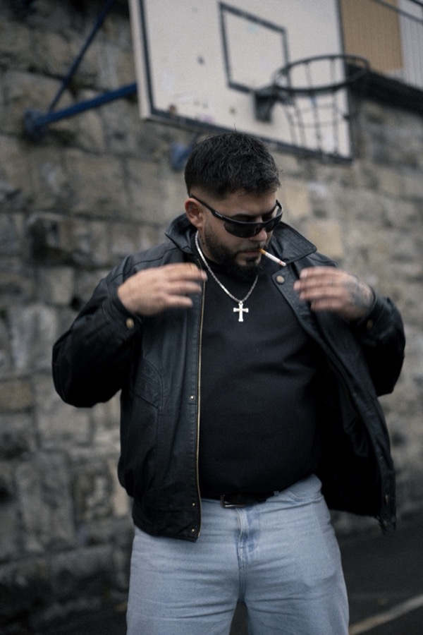 GABU richtet seine Jacke, vor einem Basketballkorb
